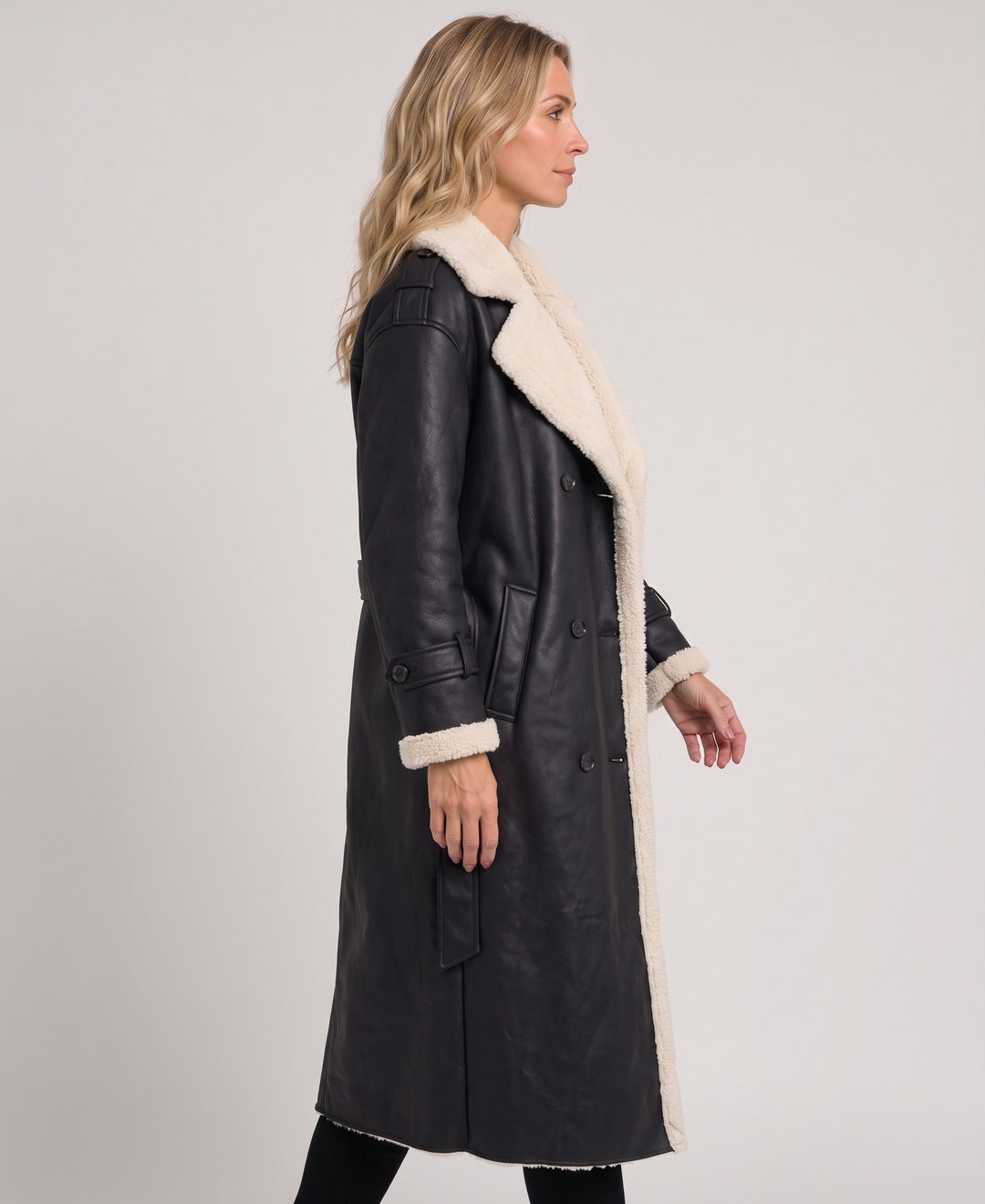 Black long faux leather coat with teddy lining, side view on model