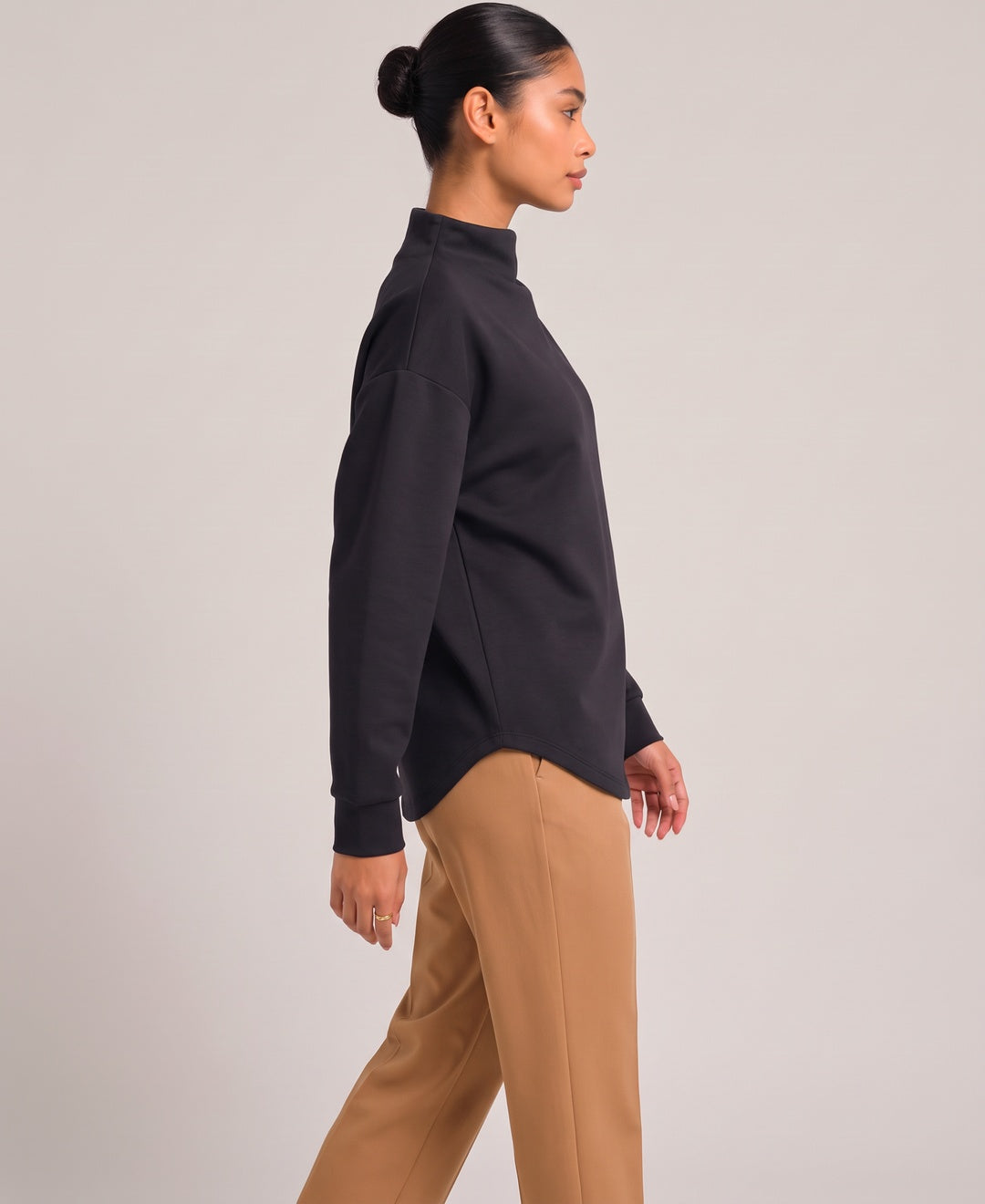 Women's oversized funnel neck top in black, side view